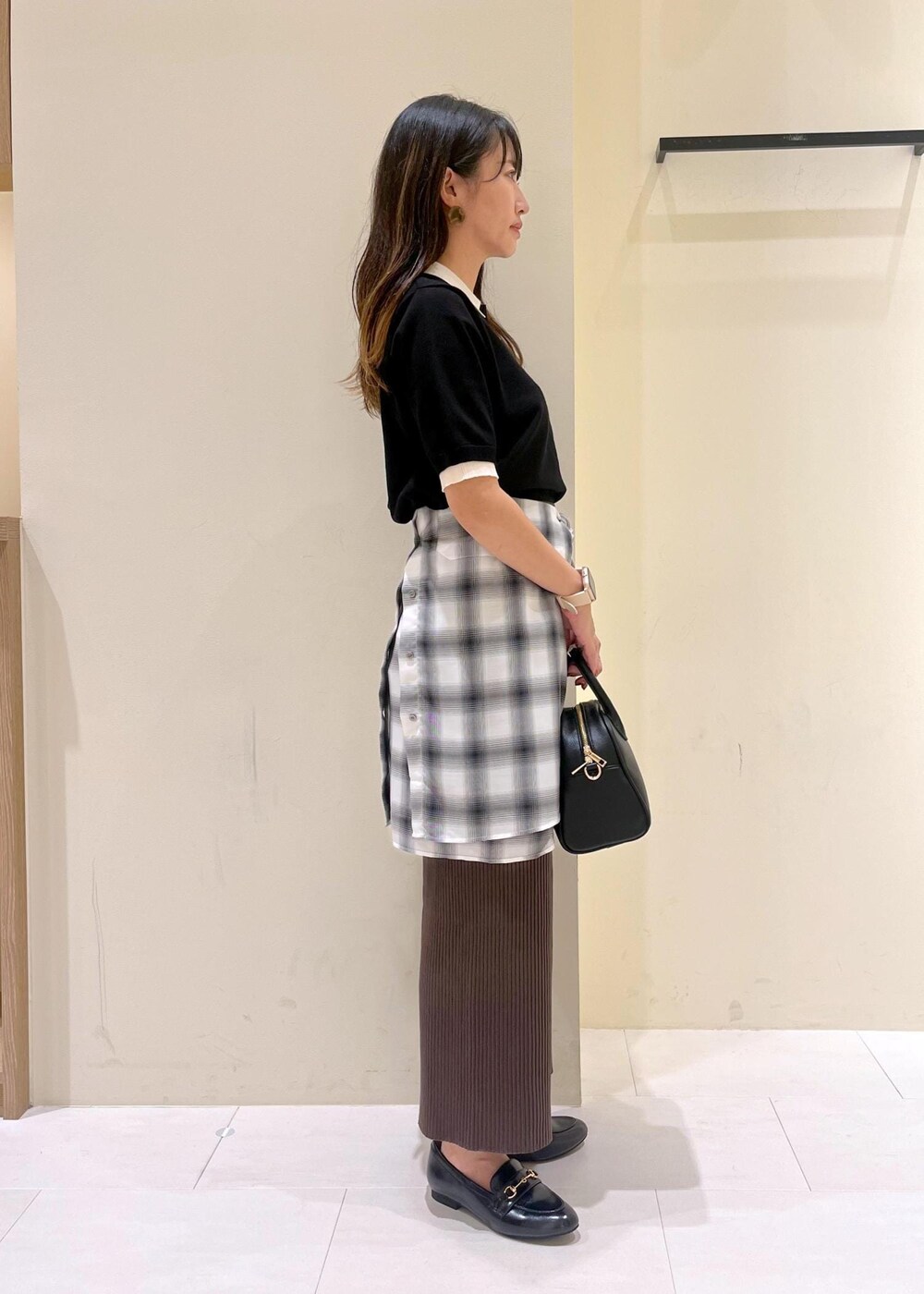 ブラック系のスカート、ブラック系のボストンバッグ、ブラック系のポロシャツを着用したレディースの夏コーディネートの3枚目の写真