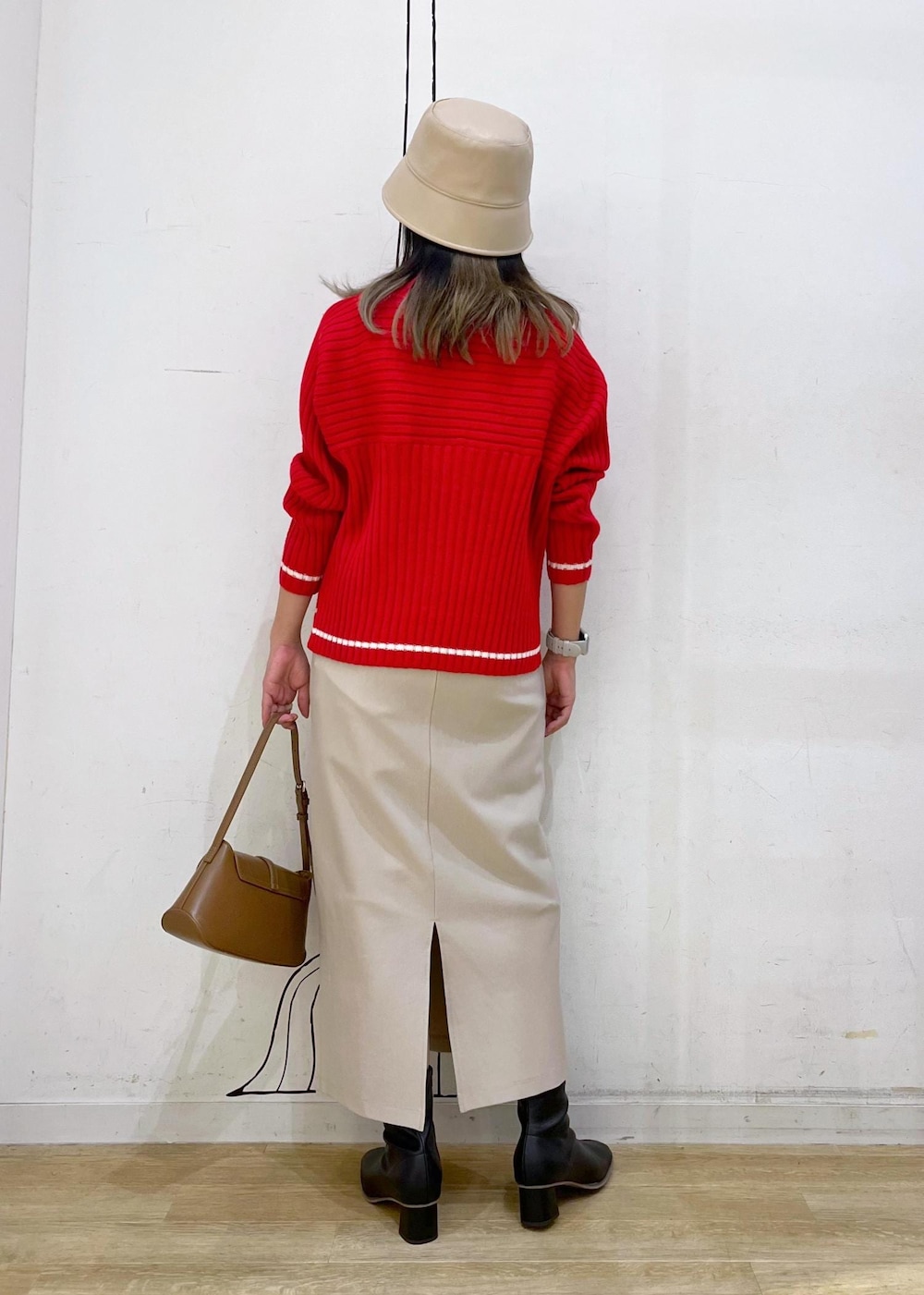 ベージュ系のスカート、レッド系のニット/セーター、ブラック系のブーツを着用したレディースの秋コーディネートの5枚目の写真