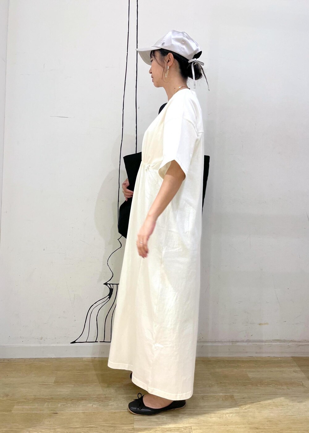 ブラック系のトートバッグ、ブラック系のバレエシューズ、ホワイト系のワンピースを着用したレディースの夏コーディネートの2枚目の写真