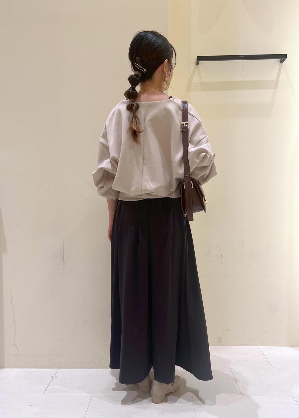 レッド系のショルダーバッグ、ベージュ系のパンプス、ベージュ系のカーディガン/ボレロを着用したレディースの秋コーディネートの4枚目の写真