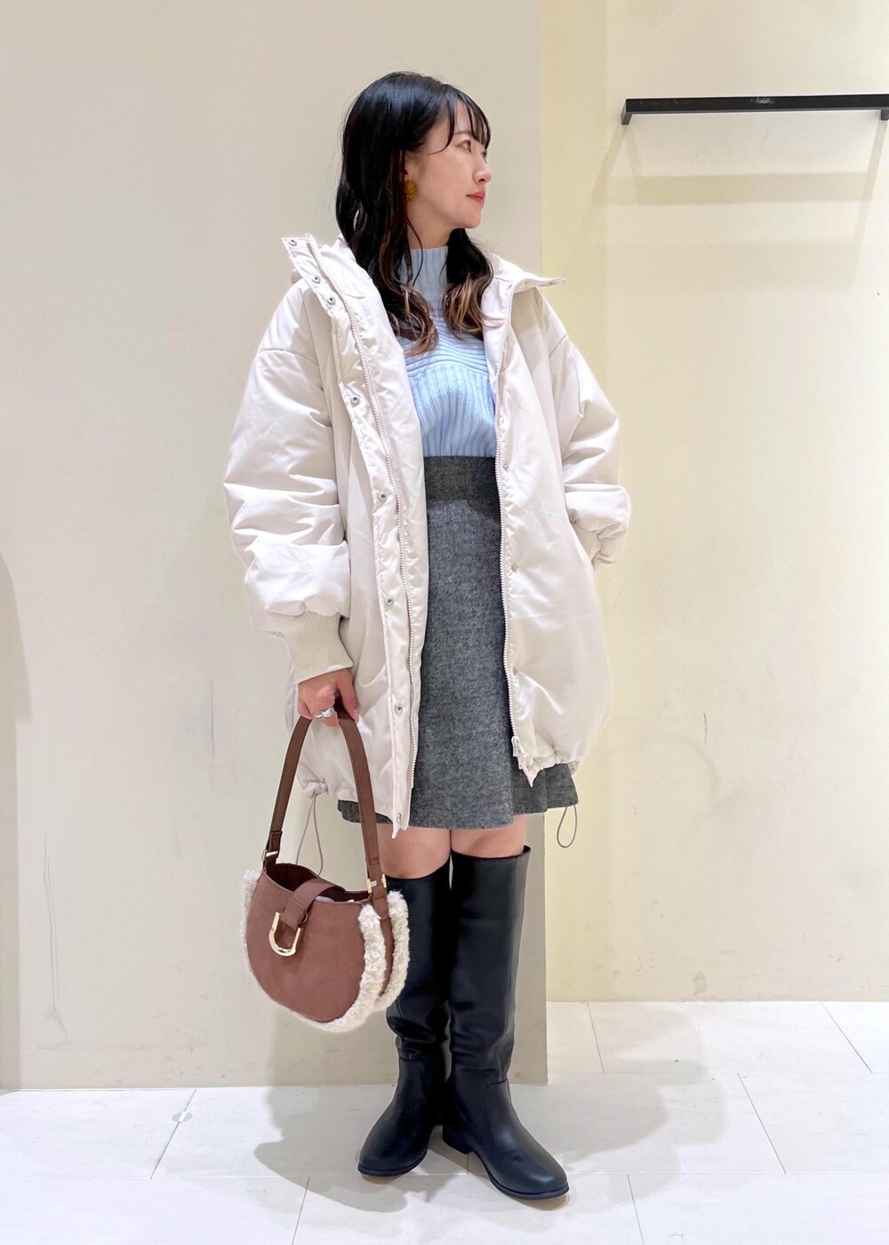 ブラック系のブーツ、ブラウン系のショルダーバッグ、ブルー系のニット/セーターを着用したレディースの冬コーディネートの10枚目の写真