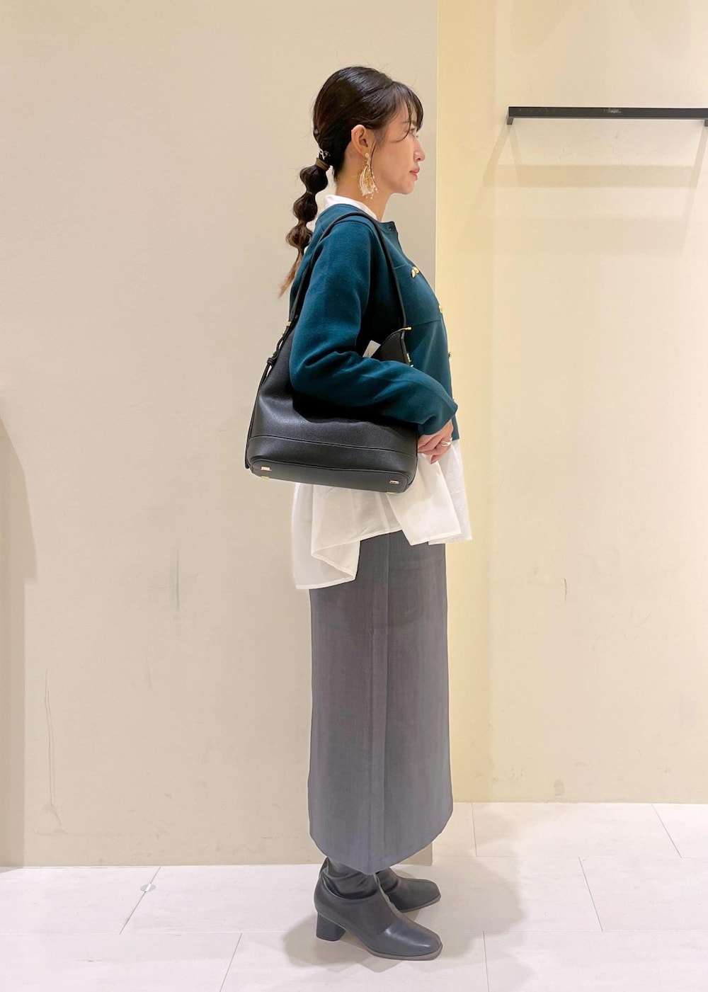 グレー系のスカート、ホワイト系のシャツ/ブラウス、グリーン系のカーディガン/ボレロを着用したレディースの秋コーディネートの2枚目の写真