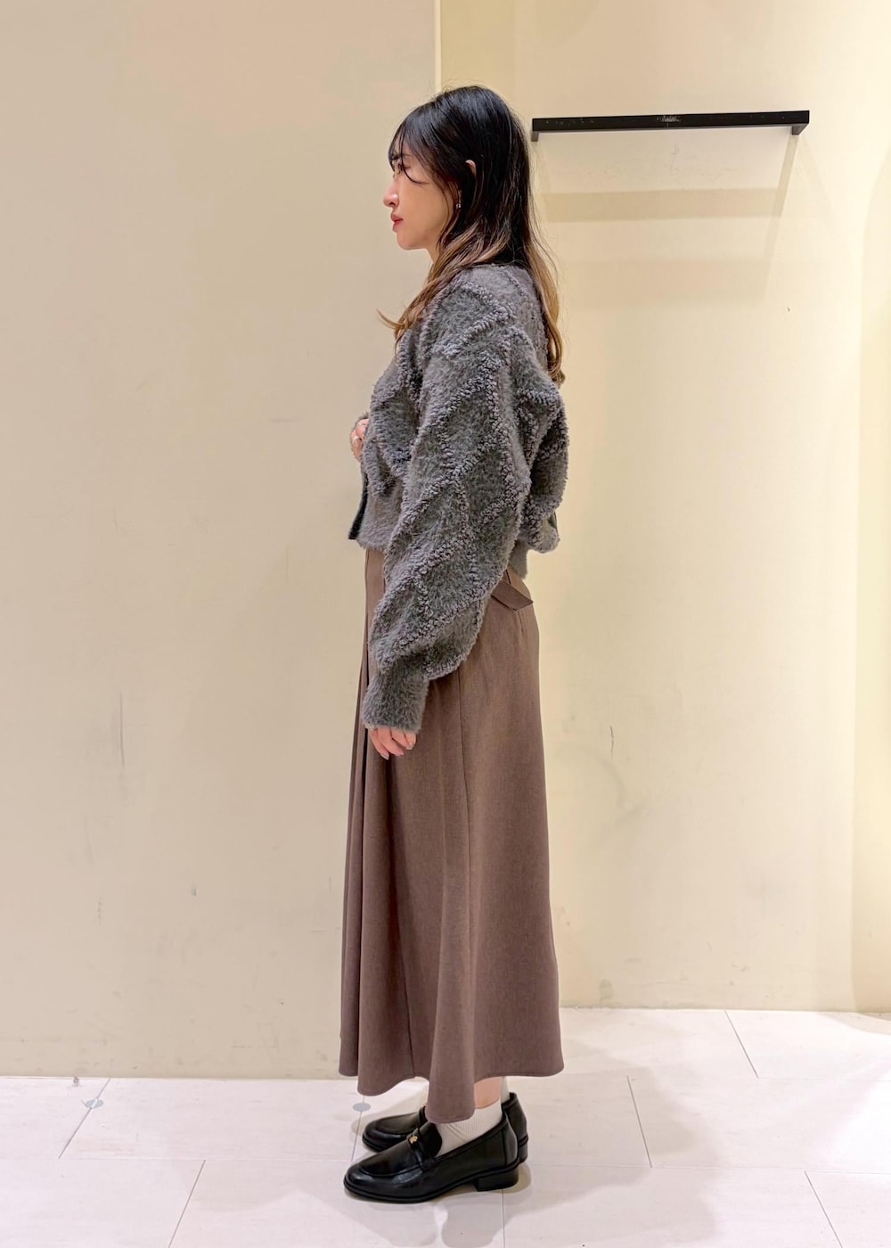 ベージュ系のスカート、グレー系のカーディガン/ボレロ、ホワイト系のTシャツ/カットソーを着用したレディースの冬コーディネートの4枚目の写真