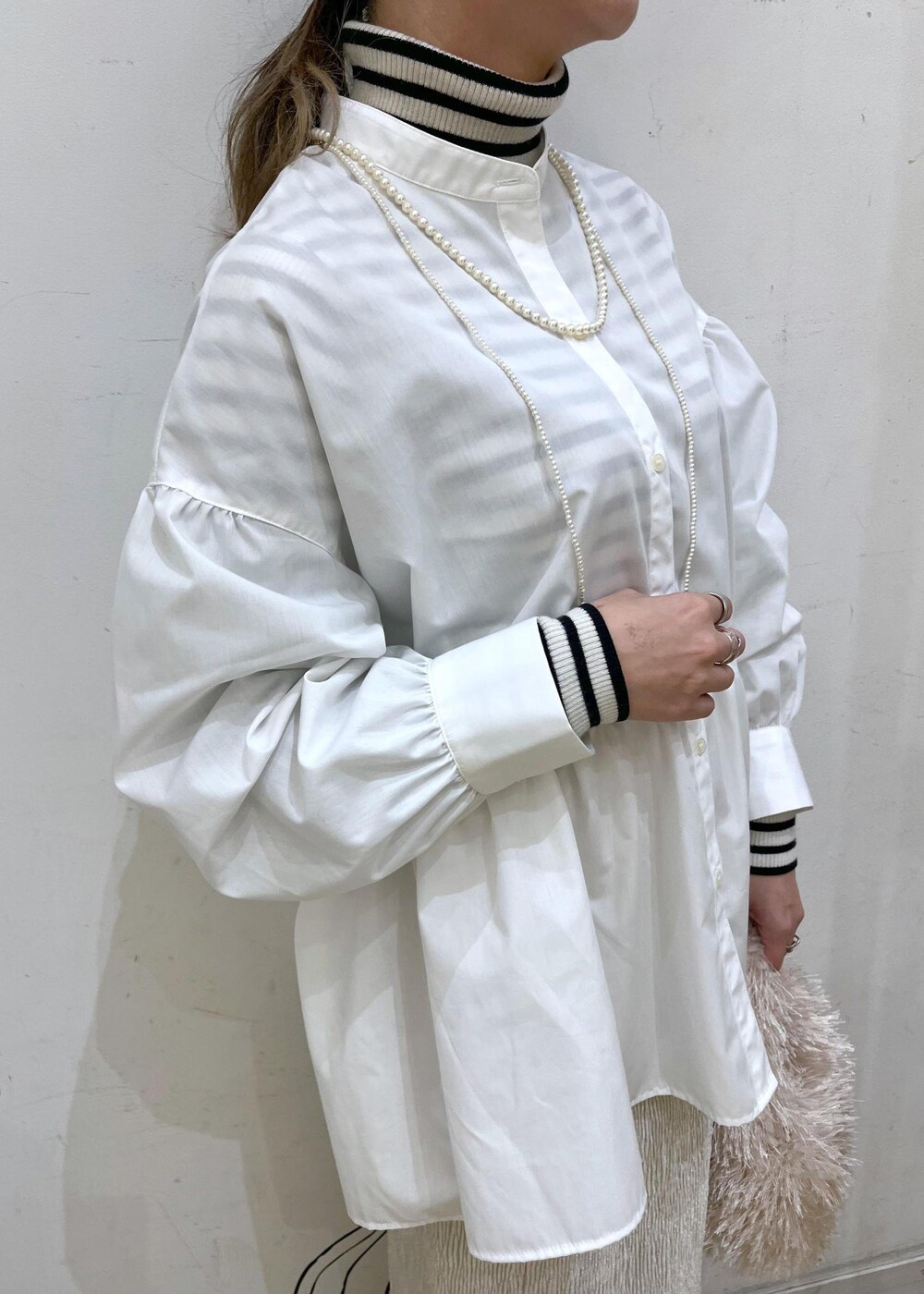 ベージュ系のハンドバッグ、ホワイト系のニット/セーター、シルバー系のバレエシューズを着用したレディースの冬コーディネートの6枚目の写真