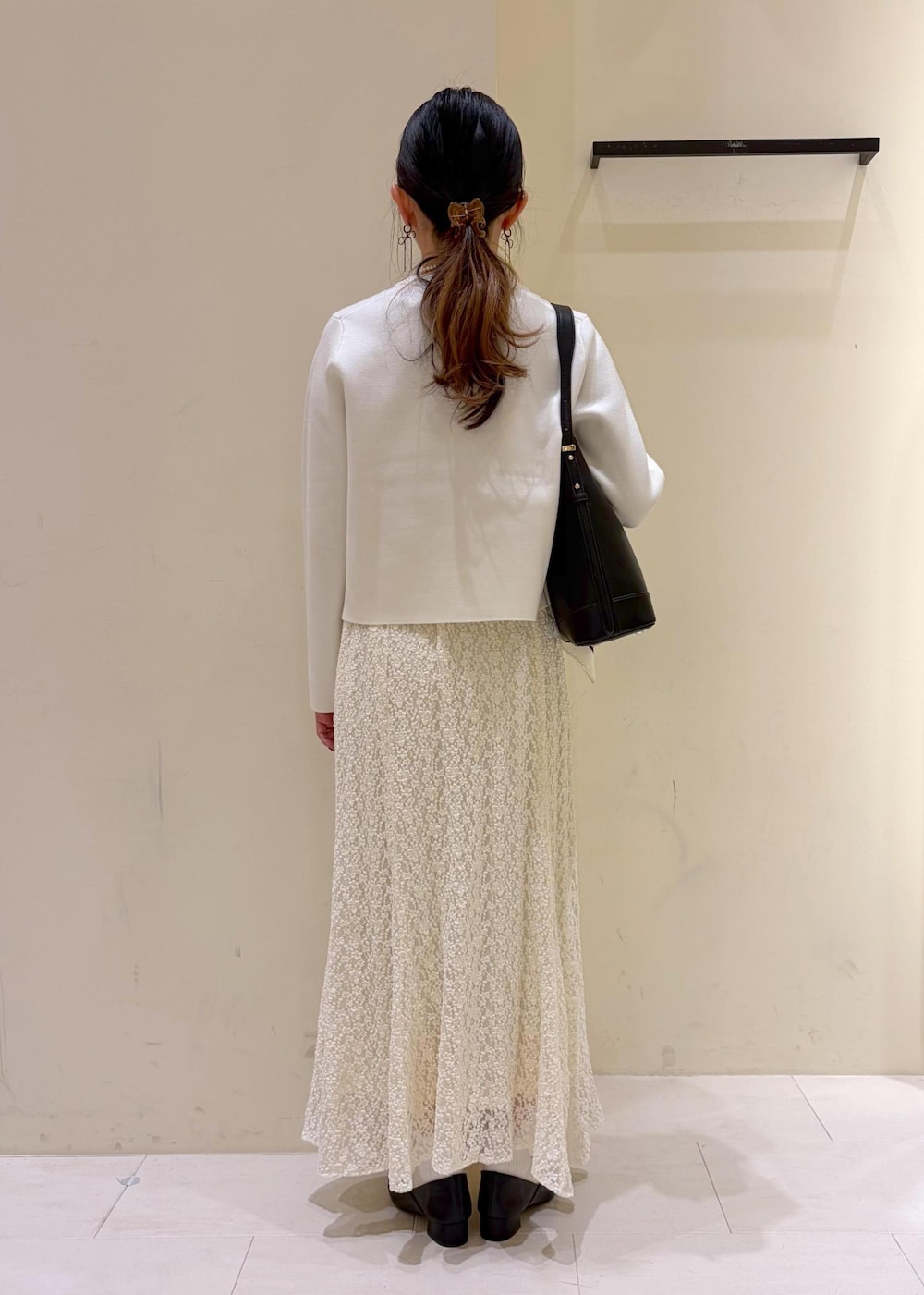 ブラック系のショルダーバッグ、ホワイト系のカーディガン/ボレロ、ホワイト系のスカートを着用したレディースの冬コーディネートの3枚目の写真