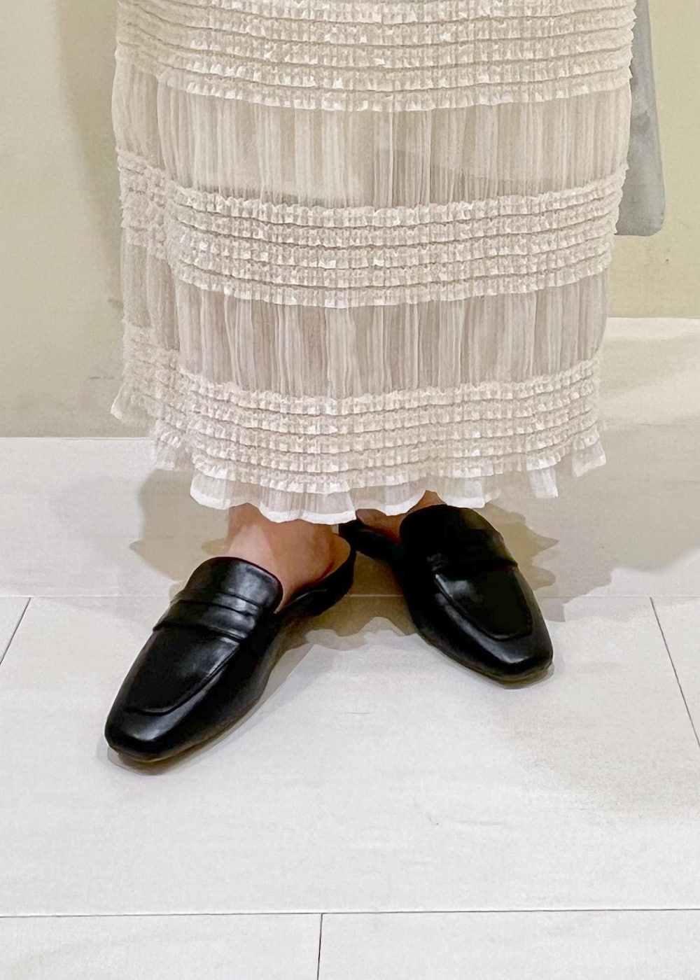 シルバー系のトートバッグ、ブラック系のローファー、ベージュ系のTシャツ/カットソーを着用したレディースの春コーディネートの9枚目の写真