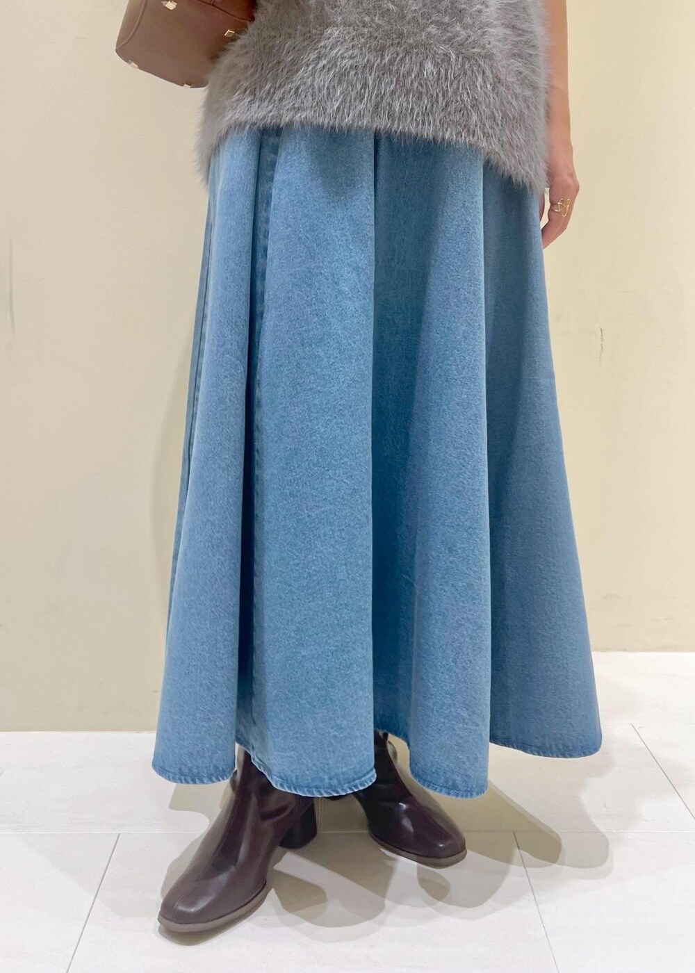 グレー系のタンクトップ、ブルー系のスカート、グレー系のベストを着用したレディースの秋コーディネートの8枚目の写真