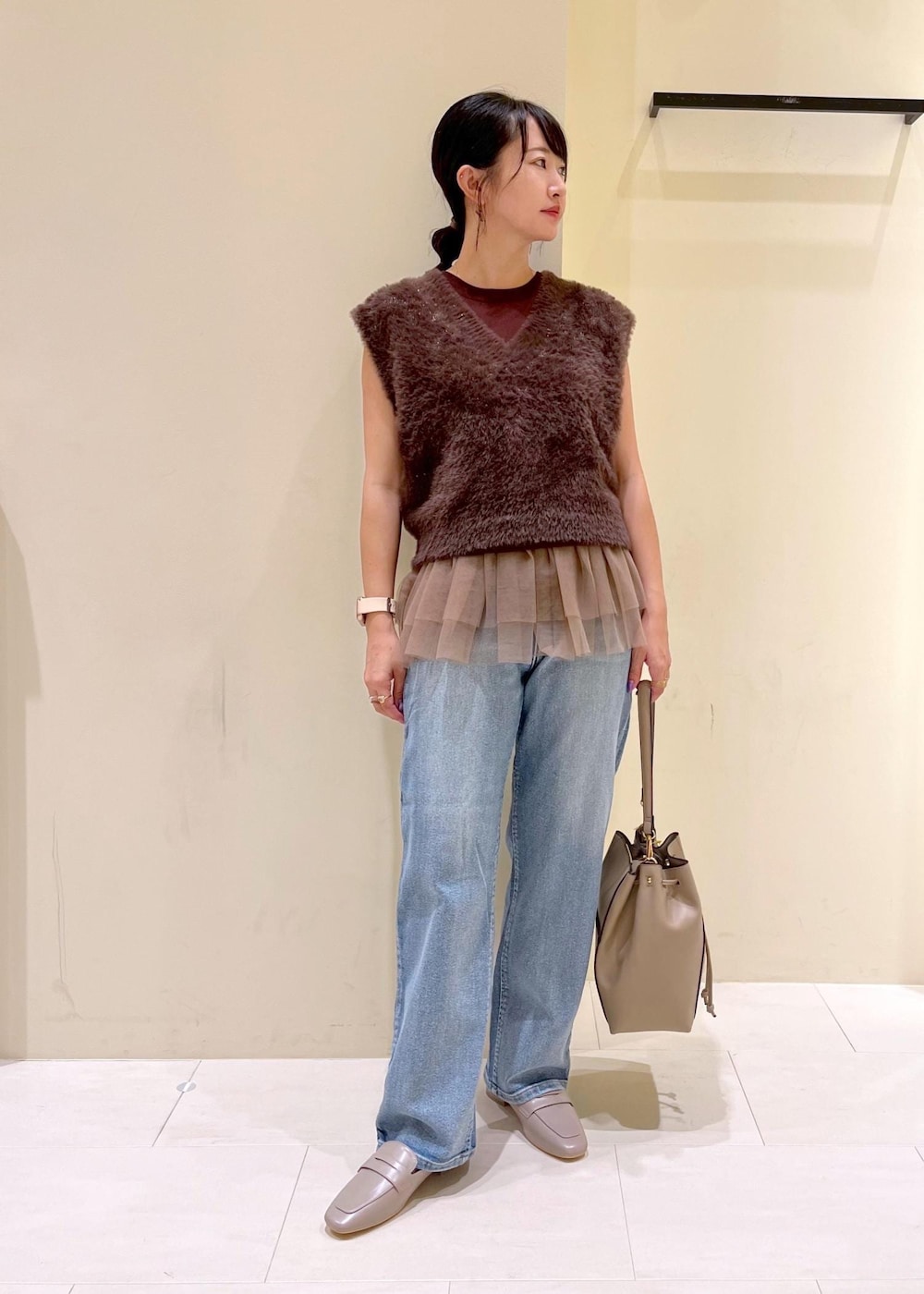 グレー系のローファー、ブルー系のデニムパンツ、ベージュ系のショルダーバッグを着用したレディースの夏コーディネートの2枚目の写真