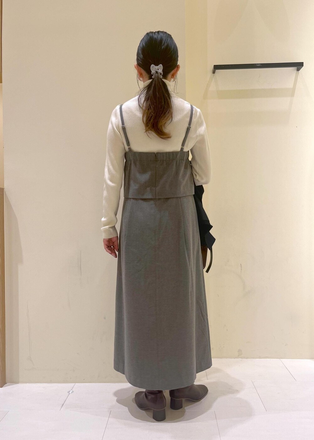 レッド系のショルダーバッグ、ホワイト系のニット/セーター、グレー系のワンピースを着用したレディースの秋コーディネートの10枚目の写真
