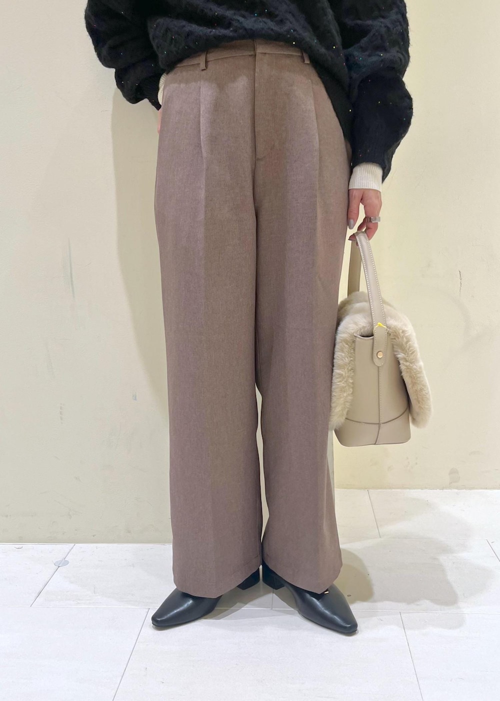 ベージュ系のスラックス、ホワイト系のニット/セーター、ベージュ系のショルダーバッグを着用したレディースの冬コーディネートの8枚目の写真