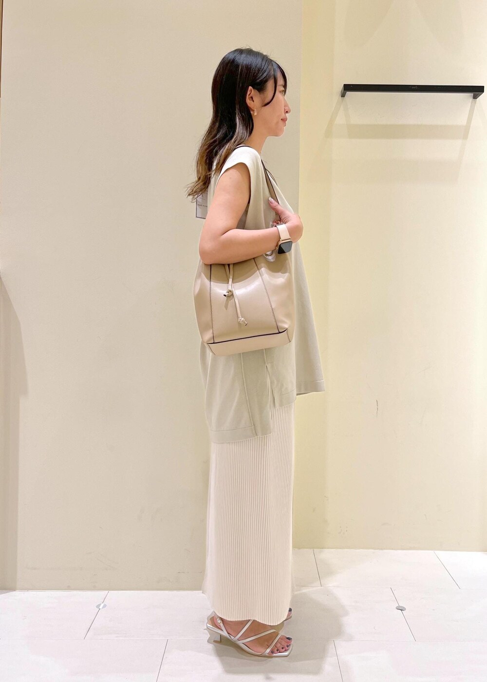 ベージュ系のタンクトップ、シルバー系のサンダル、ベージュ系のショルダーバッグを着用したレディースの夏コーディネートの3枚目の写真