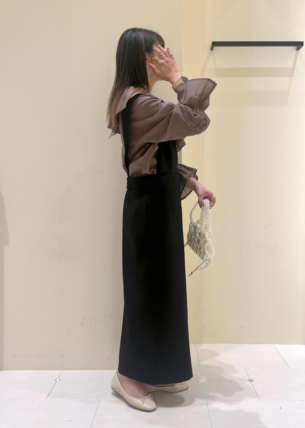 ホワイト系のバレエシューズ、ブラウン系のシャツ/ブラウス、ブラック系のジャンパースカートを着用したレディースの春コーディネートの4枚目の写真