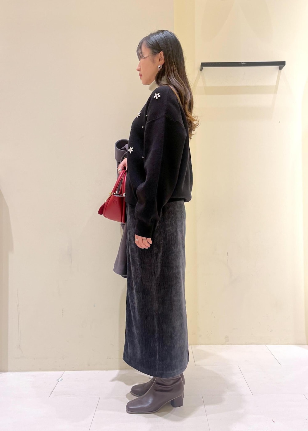 グレー系のスカート、ブラック系のカーディガン/ボレロ、ホワイト系のニット/セーターを着用したレディースの冬コーディネートの2枚目の写真