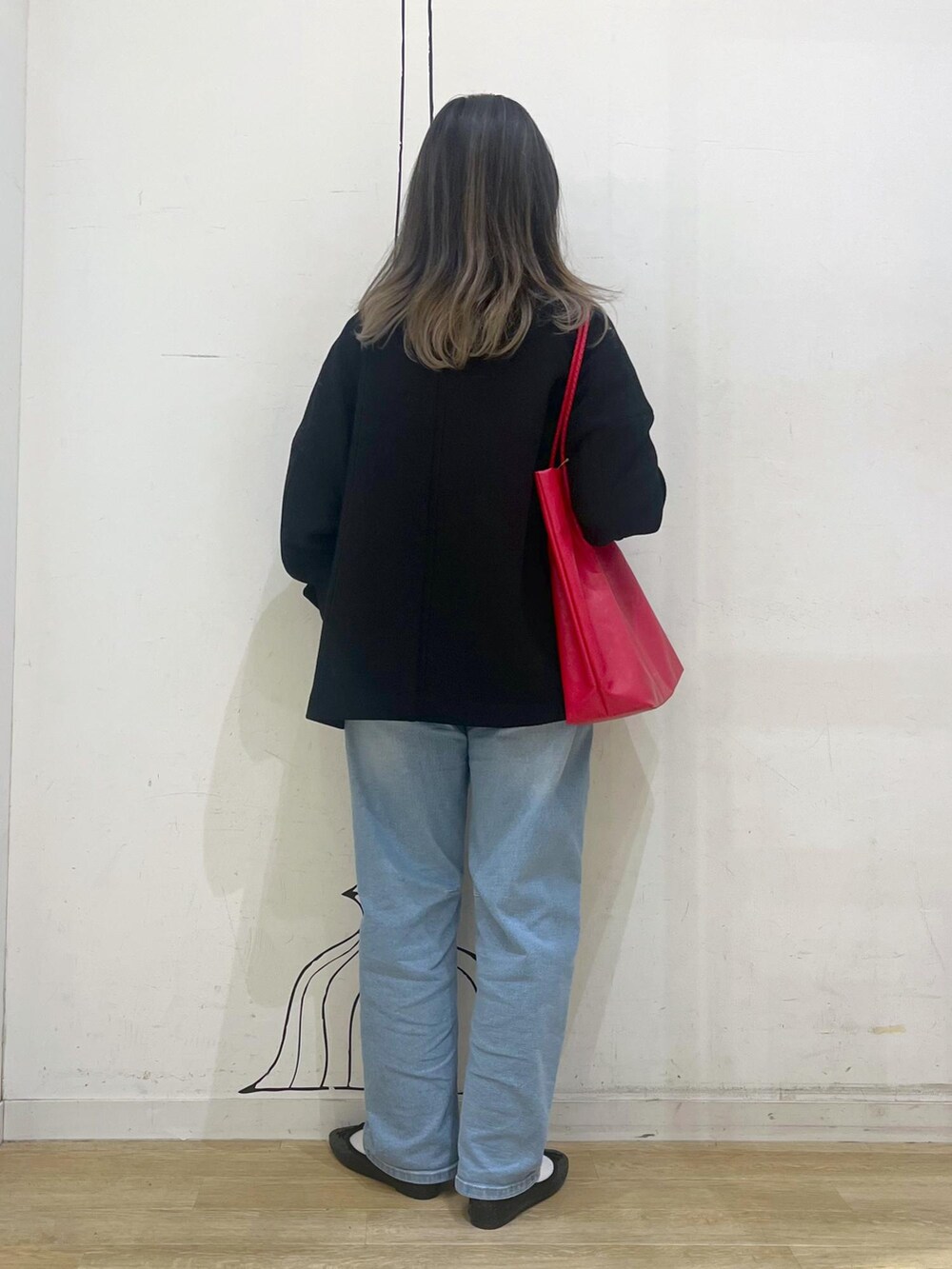 ブルー系のデニムパンツ、レッド系のトートバッグ、ブラック系のその他アウターを着用したレディースの冬コーディネートの3枚目の写真