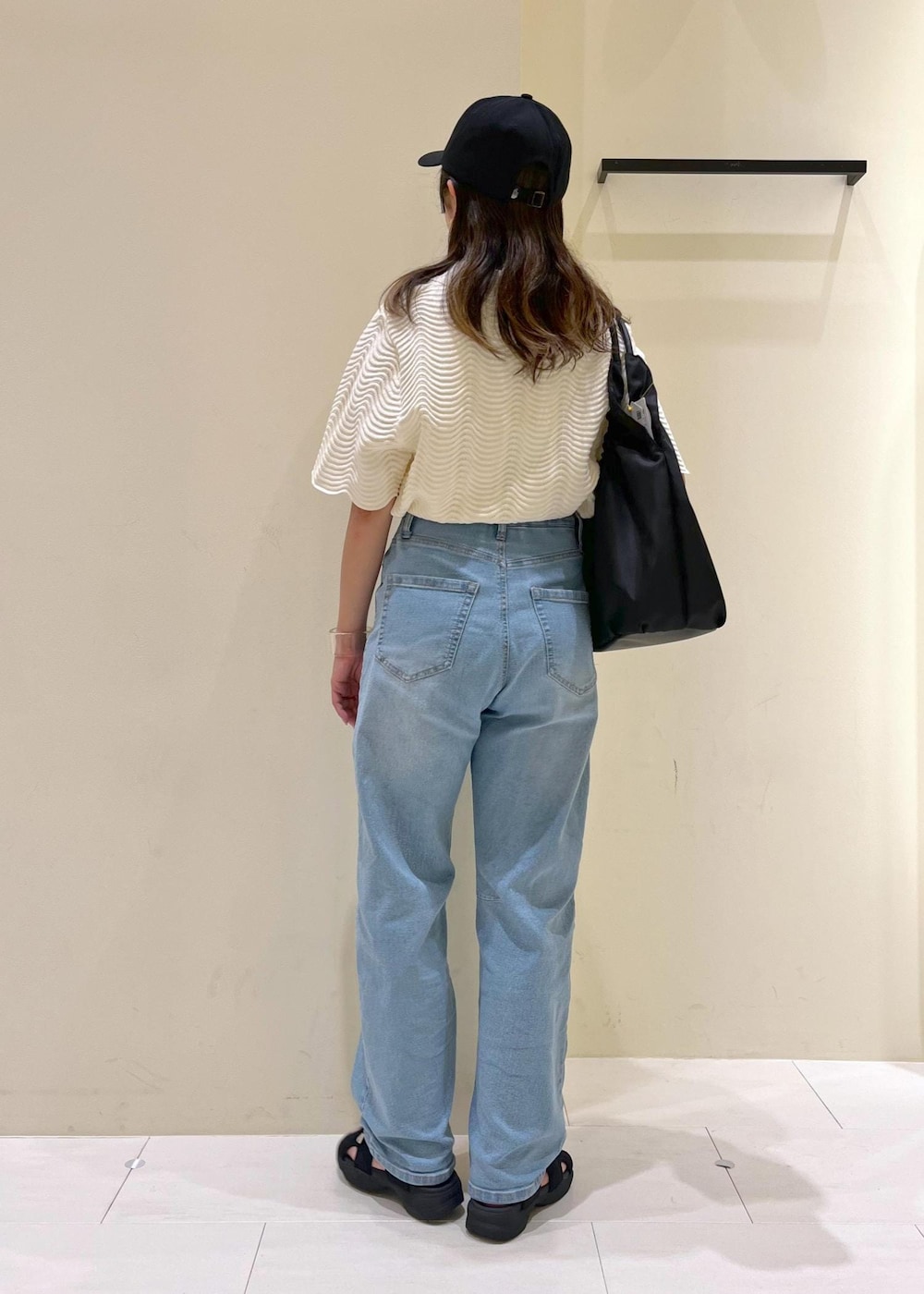 ブルー系のデニムパンツ、ホワイト系のニット/セーター、ブラック系のサンダルを着用したレディースの夏コーディネートの4枚目の写真