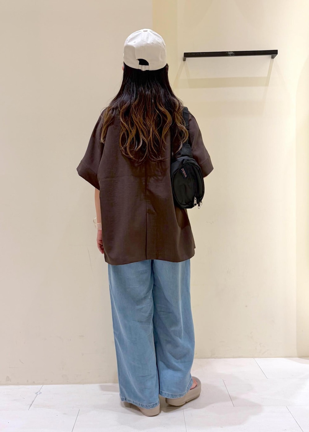 ブルー系のデニムパンツ、ブラウン系のテーラードジャケット、ブラック系のキャミソールを着用したレディースの夏コーディネートの3枚目の写真