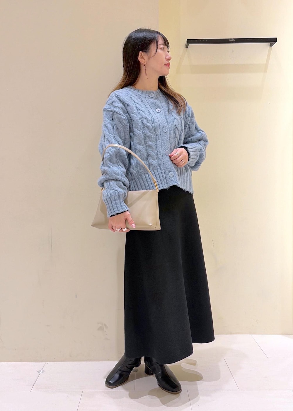 ブラック系のブーツ、ベージュ系のショルダーバッグ、ブラック系のワンピースを着用したレディースの冬コーディネートの2枚目の写真