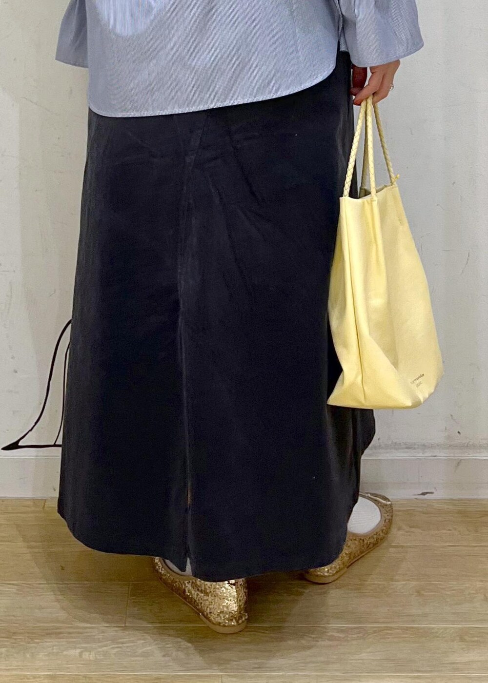 イエロー系のトートバッグ、グレー系のスカート、ブルー系のシャツ/ブラウスを着用したレディースの冬コーディネートの8枚目の写真