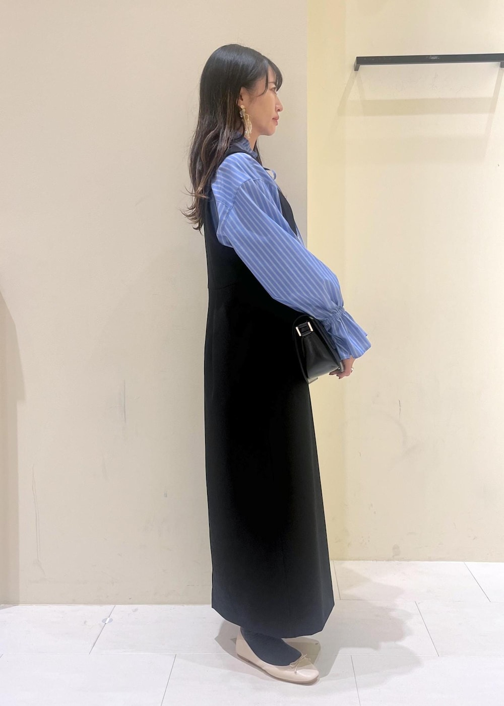 ホワイト系のバレエシューズ、ブラック系のショルダーバッグ、ブラック系のジャンパースカートを着用したレディースの冬コーディネートの3枚目の写真