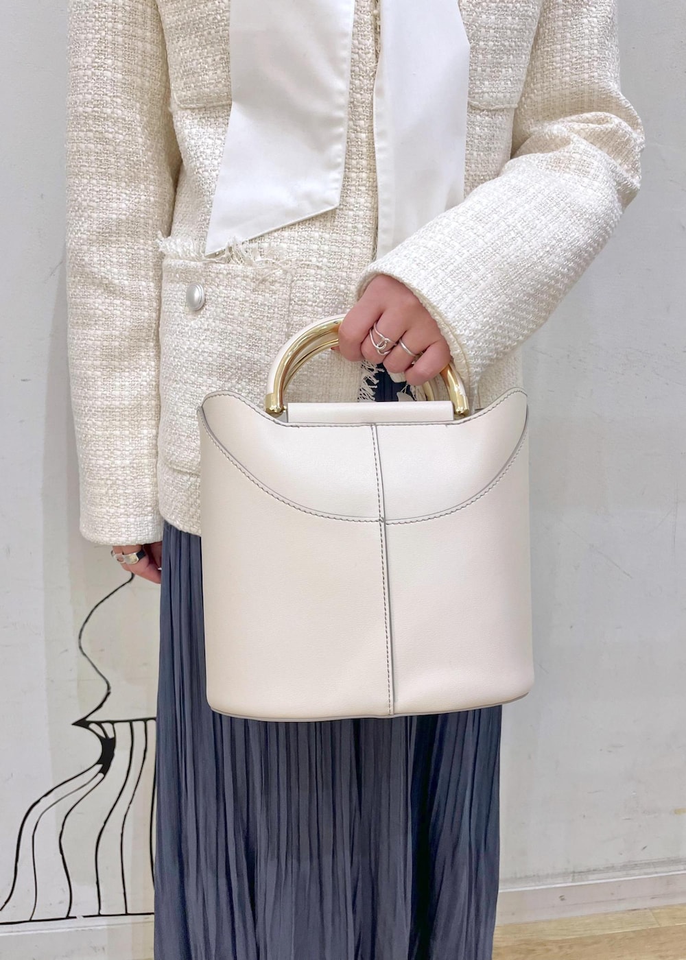 ブルー系のスカート、ベージュ系のローファー、ホワイト系のショルダーバッグを着用したレディースの冬コーディネートの8枚目の写真