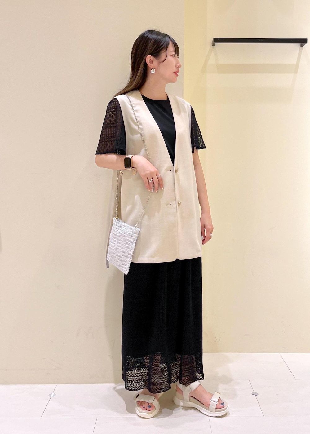 その他のショルダーバッグ、ベージュ系のベスト、ホワイト系のサンダルを着用したレディースの春コーディネートの2枚目の写真