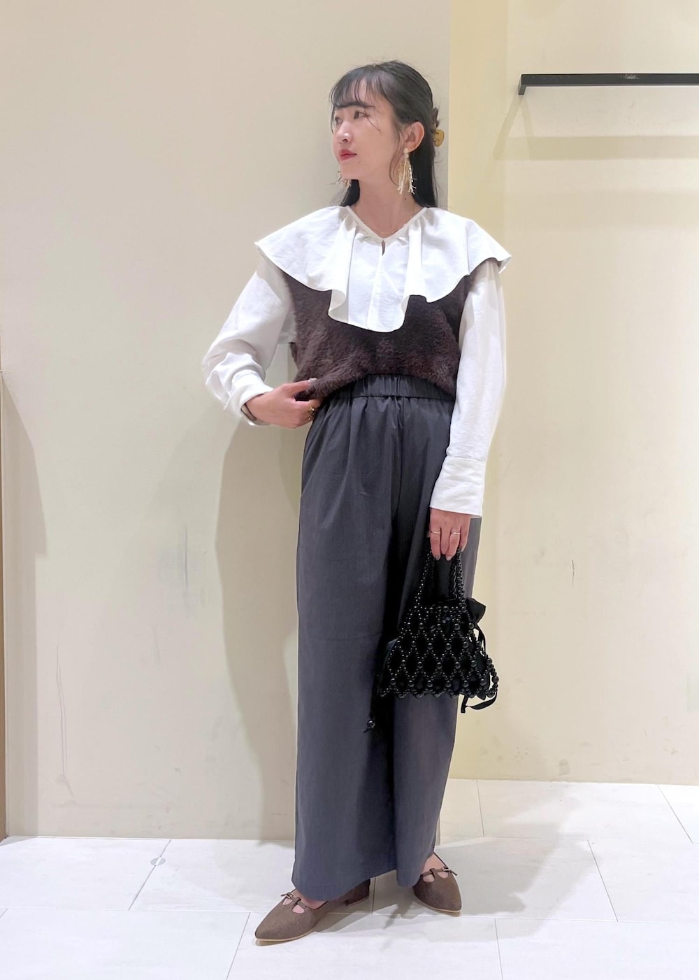 ホワイト系のシャツ/ブラウス、ブラック系のハンドバッグ、ブラウン系のベストを着用したレディースの秋コーディネートの2枚目の写真