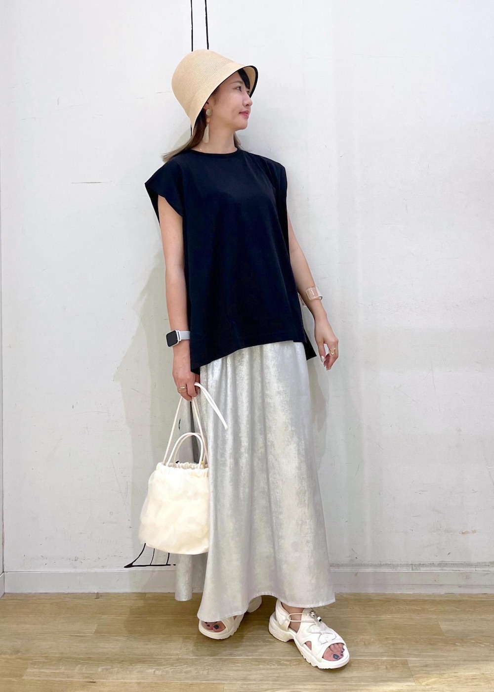 シルバー系のスカート、ブラック系のTシャツ/カットソー、ホワイト系のサンダルを着用したレディースの夏コーディネートの2枚目の写真