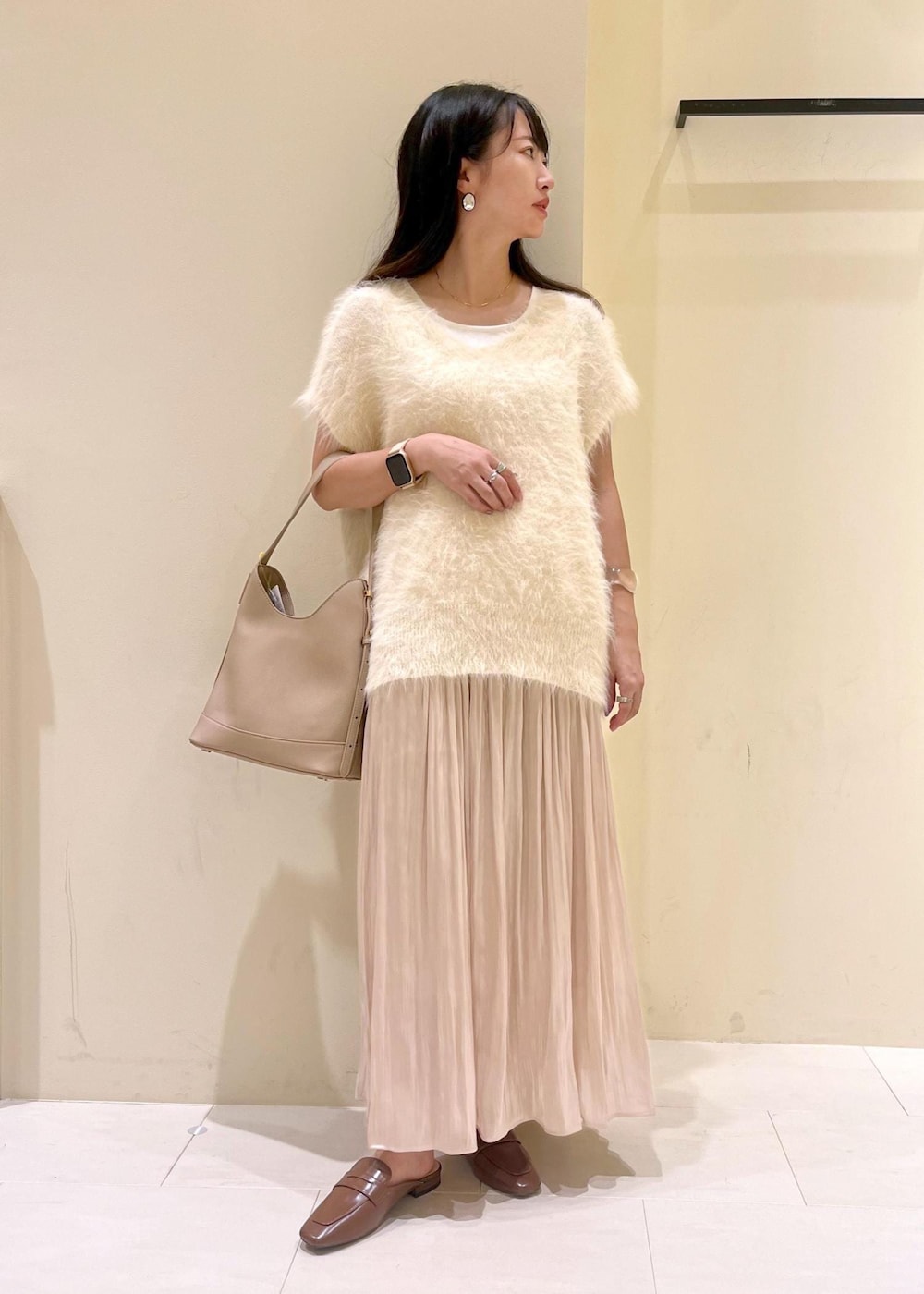 イエロー系のローファー、ベージュ系のスカート、ベージュ系のショルダーバッグを着用したレディースの夏コーディネートの2枚目の写真