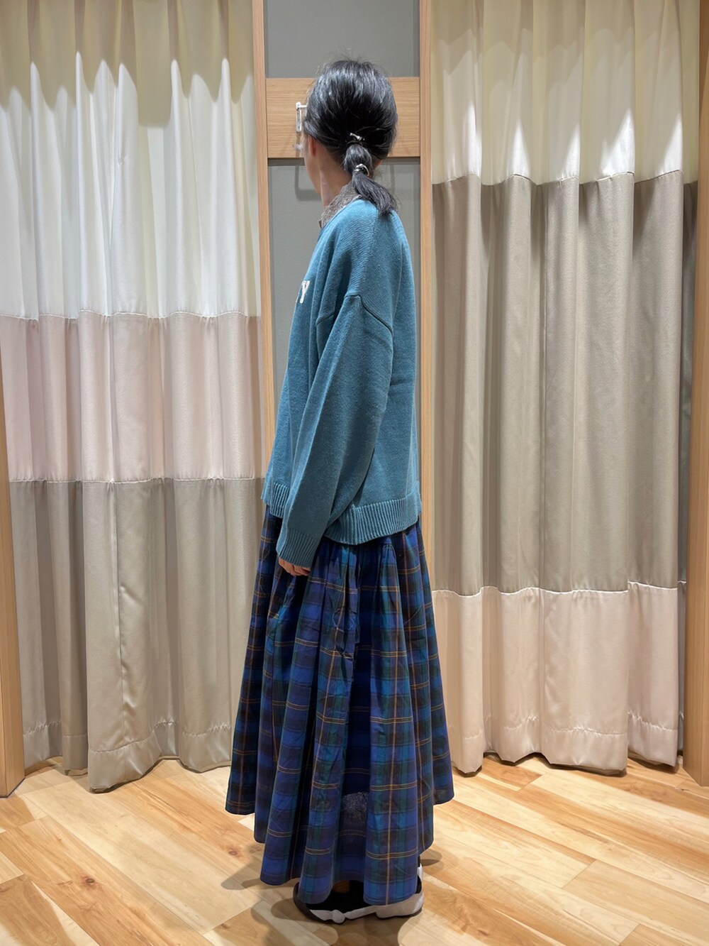 ブルー系のニット/セーター、ベージュ系のTシャツ/カットソー、ブルー系のスカートを着用したレディースの秋コーディネートの4枚目の写真