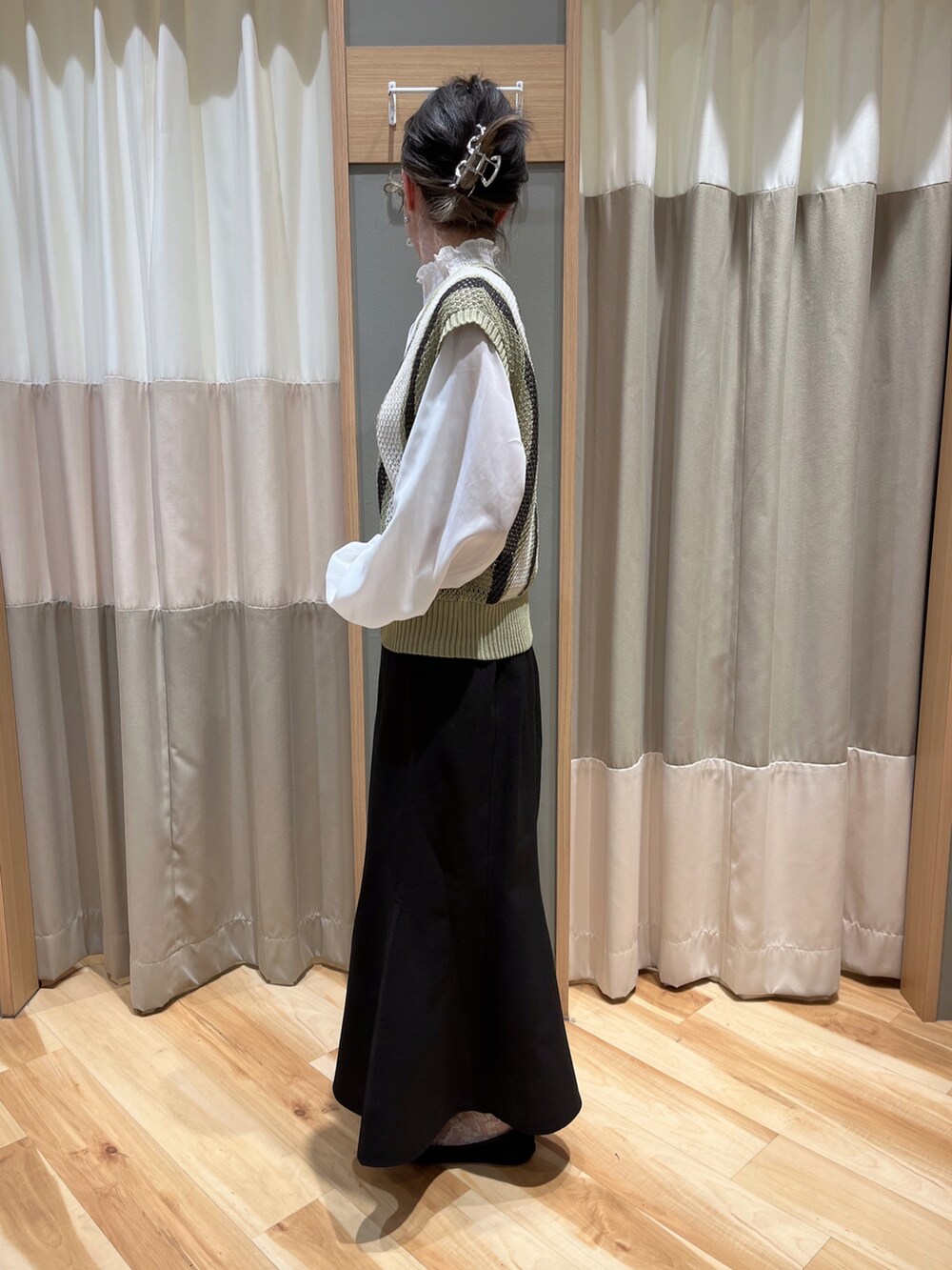 グリーン系のベスト、ブラック系のスカートを着用したレディースの春コーディネートの4枚目の写真