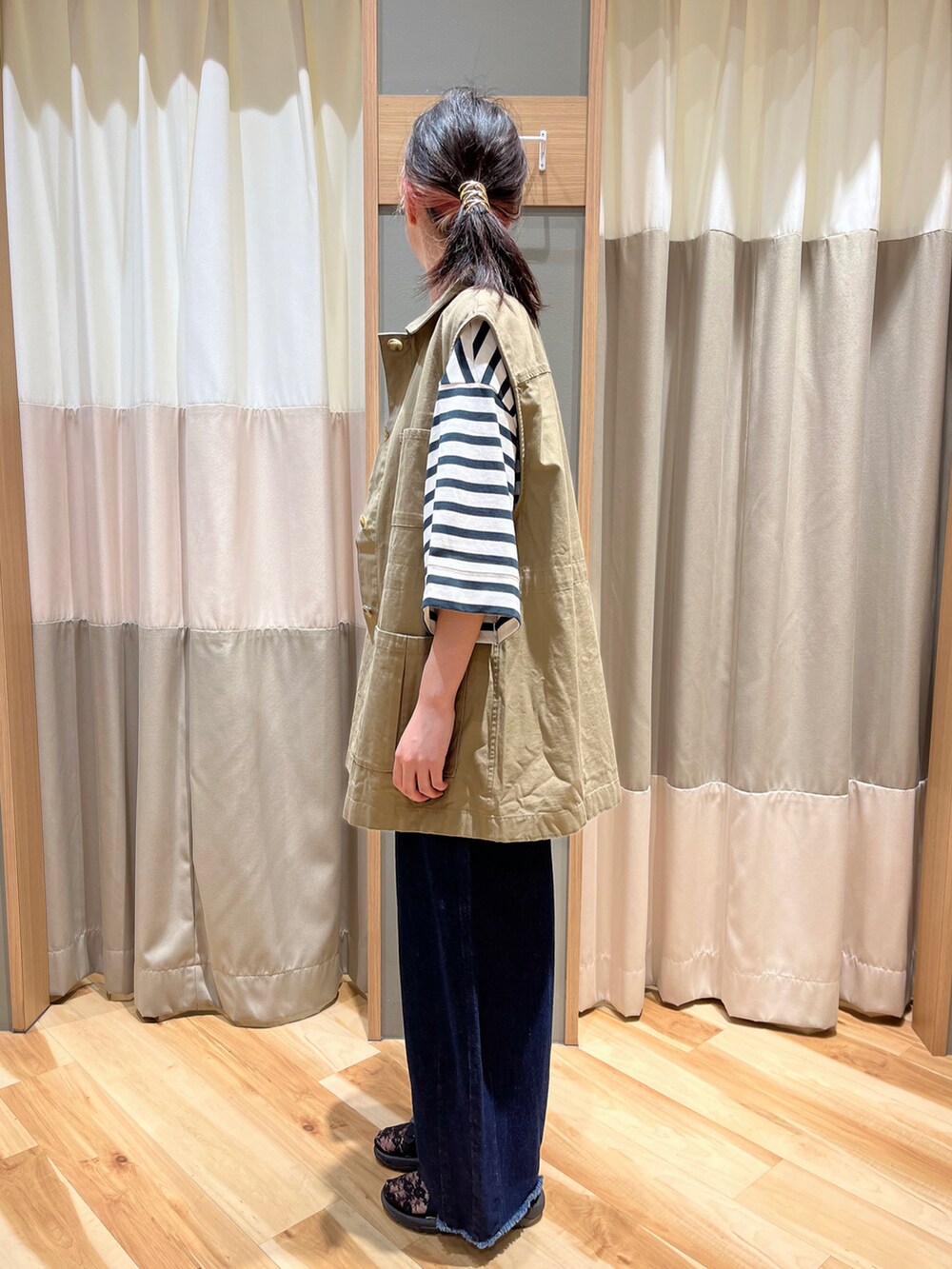 ベージュ系のベスト、グリーン系のTシャツ/カットソー、ブルー系のデニムパンツを着用したレディースの秋コーディネートの4枚目の写真