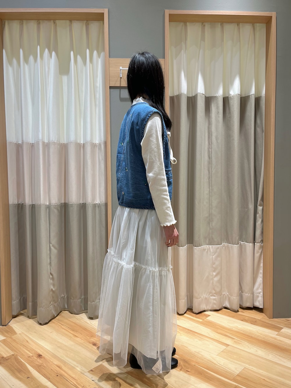 ブルー系のベスト、ホワイト系のスカート、ブラック系のその他シューズを着用したレディースの冬コーディネートの2枚目の写真