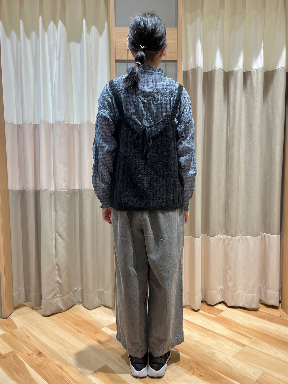 ブラック系のニット/セーター、ブルー系のシャツ/ブラウス、グレー系のデニムパンツを着用したレディースの秋コーディネートの3枚目の写真