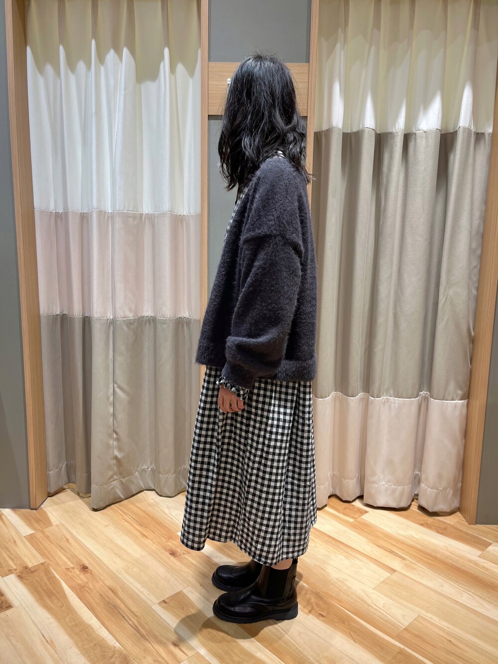 ブラック系のワンピース、グレー系のカーディガン/ボレロ、ブラック系のブーツを着用したレディースの冬コーディネートの4枚目の写真