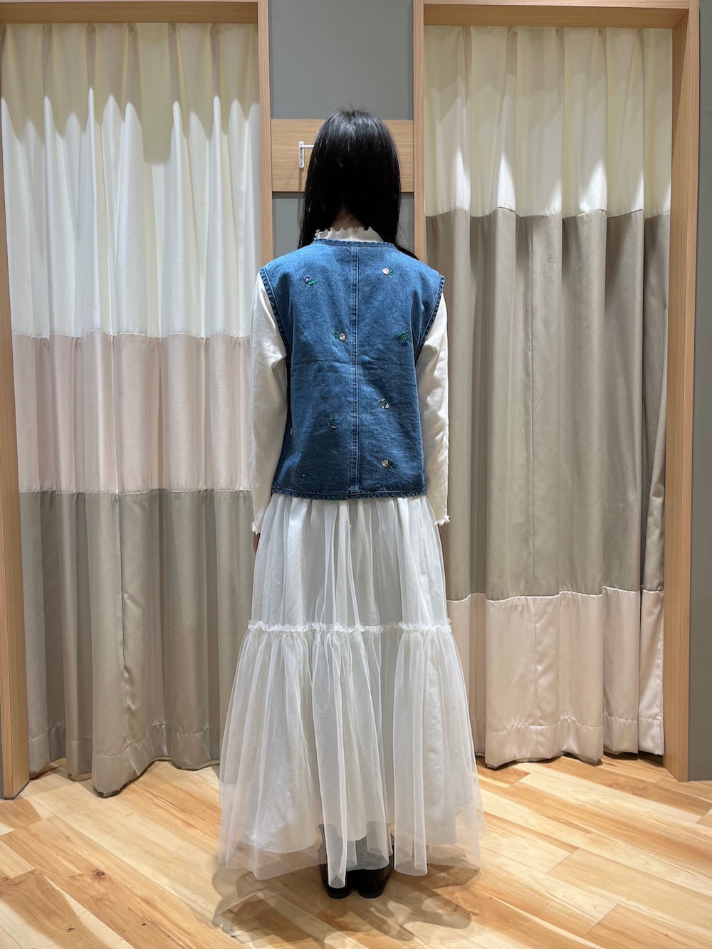 ブルー系のベスト、ホワイト系のスカート、ブラック系のその他シューズを着用したレディースの冬コーディネートの3枚目の写真