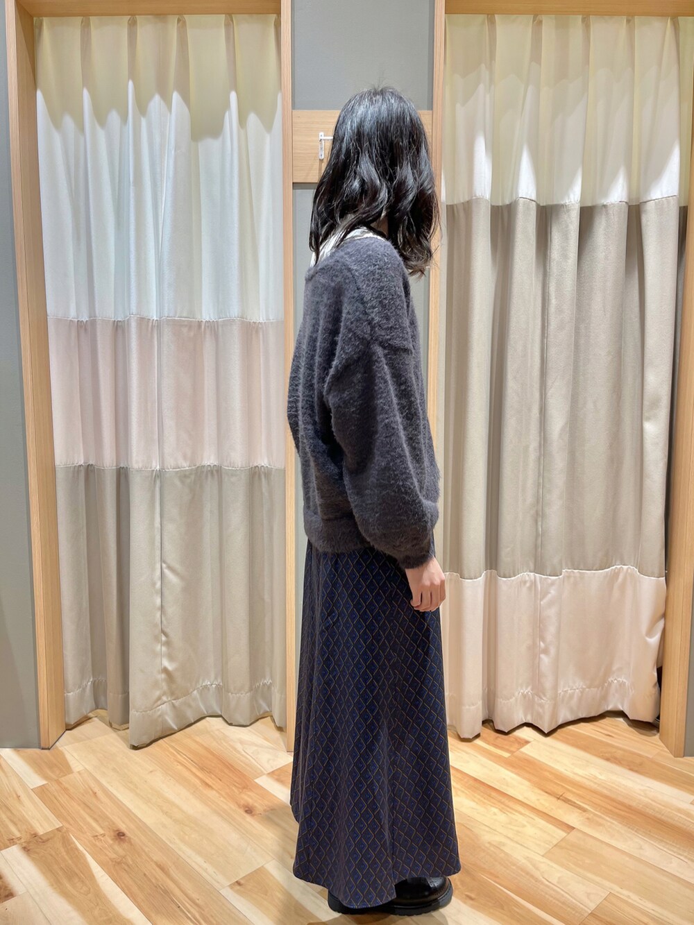 グレー系のカーディガン/ボレロ、ブルー系のスカート、ホワイト系のシャツ/ブラウスを着用したレディースの冬コーディネートの2枚目の写真