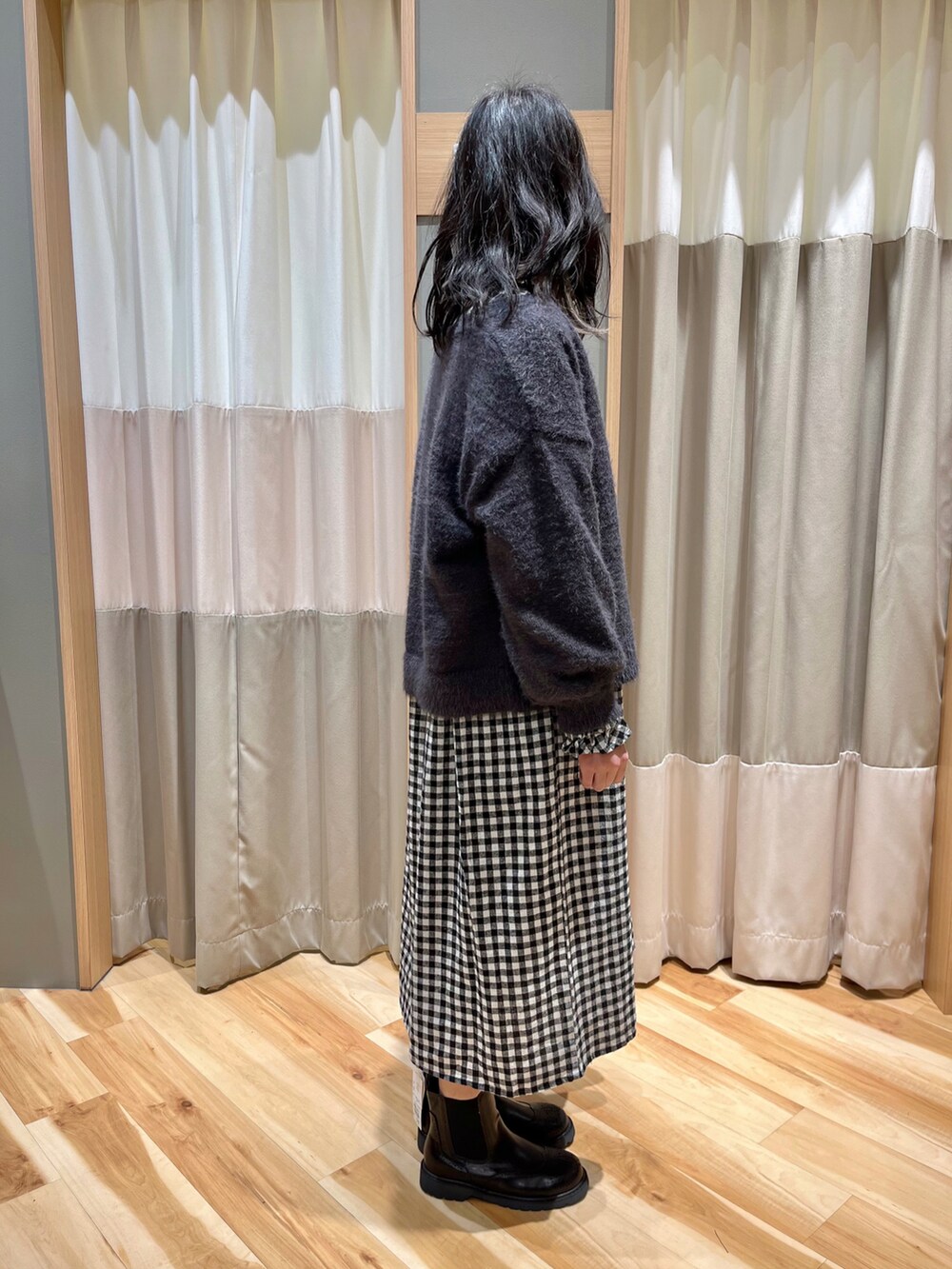 ブラック系のワンピース、グレー系のカーディガン/ボレロ、ブラック系のブーツを着用したレディースの冬コーディネートの2枚目の写真