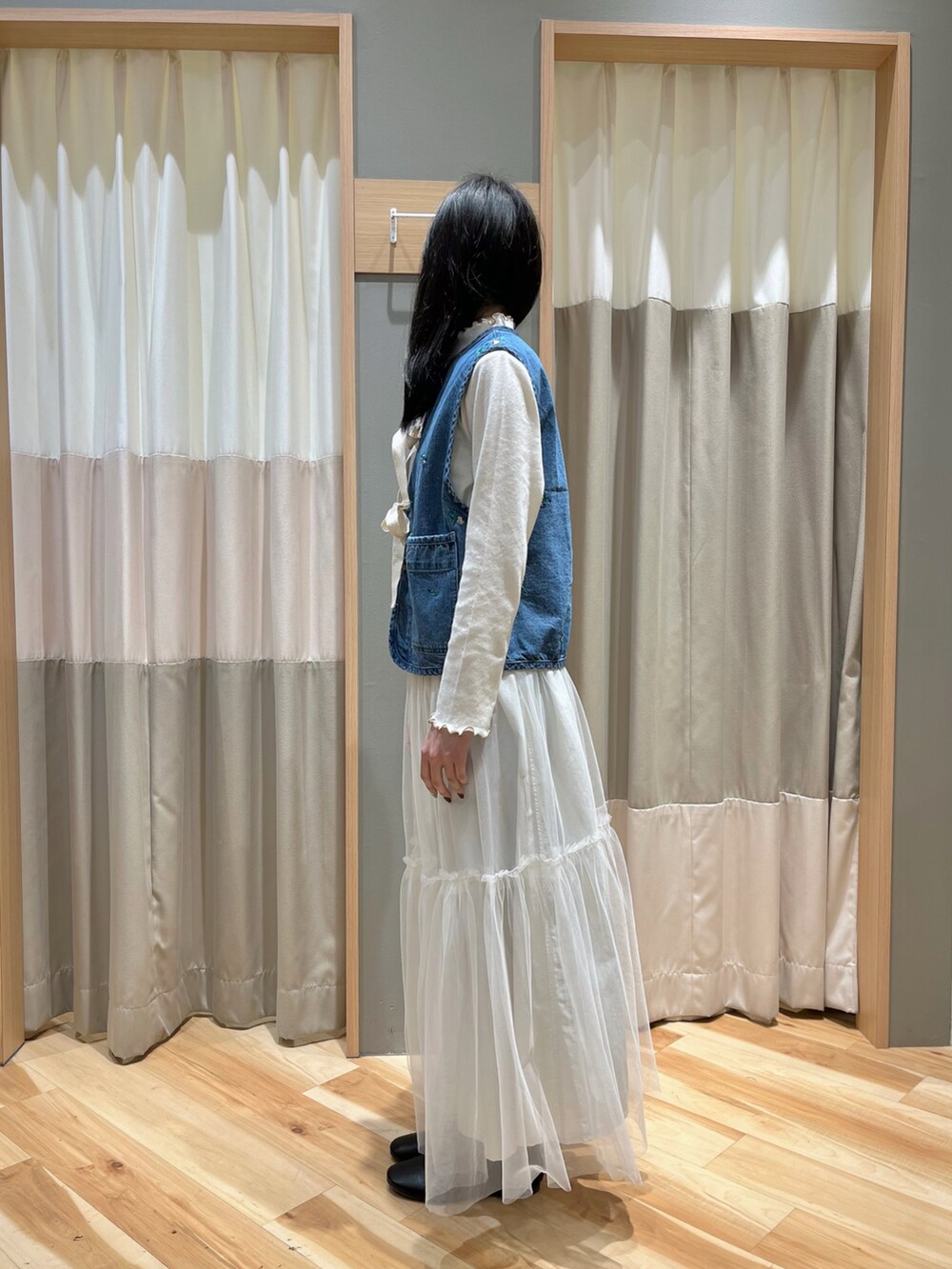 ブルー系のベスト、ホワイト系のスカート、ブラック系のその他シューズを着用したレディースの冬コーディネートの4枚目の写真