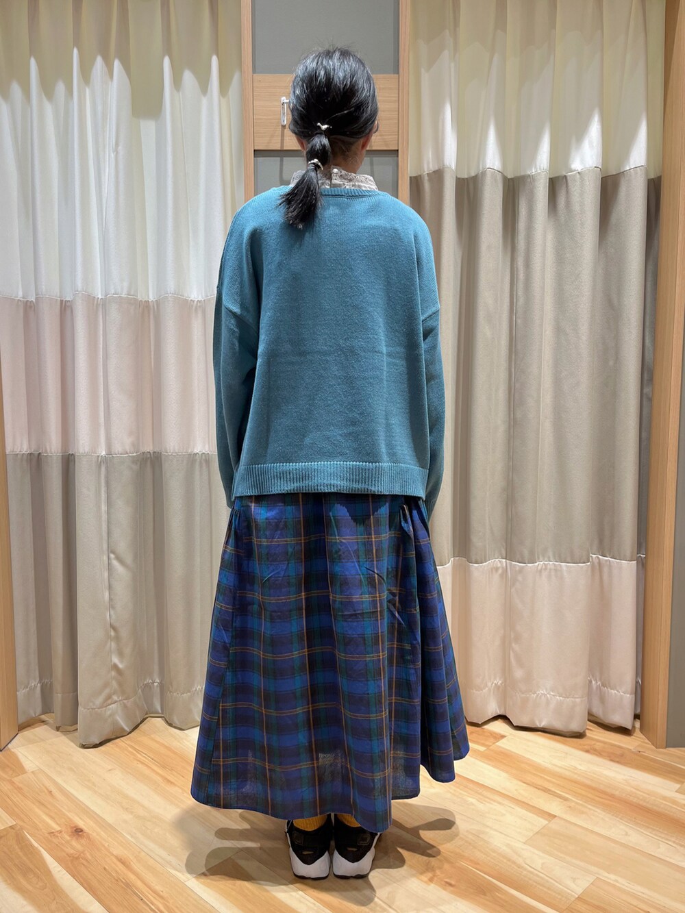 ブルー系のニット/セーター、ベージュ系のTシャツ/カットソー、ブルー系のスカートを着用したレディースの秋コーディネートの3枚目の写真