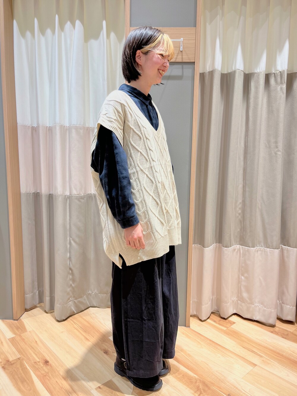 ホワイト系のベスト、ブルー系のシャツ/ブラウス、ブラック系のパンツを着用したレディースの冬コーディネートの2枚目の写真