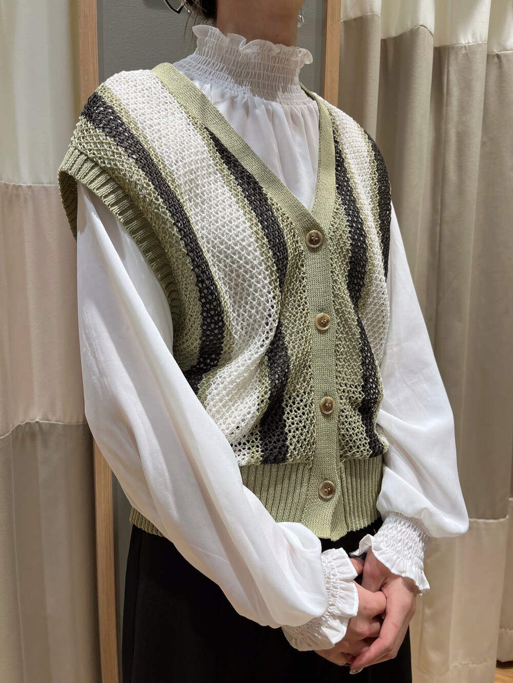 グリーン系のベスト、ブラック系のスカートを着用したレディースの春コーディネートの5枚目の写真