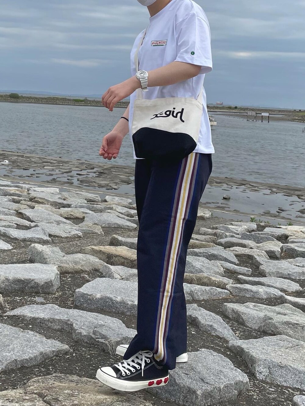 ホワイト系のTシャツ/カットソー、ベージュ系のショルダーバッグ、ブラック系のスニーカーを着用したレディースの春コーディネートの2枚目の写真