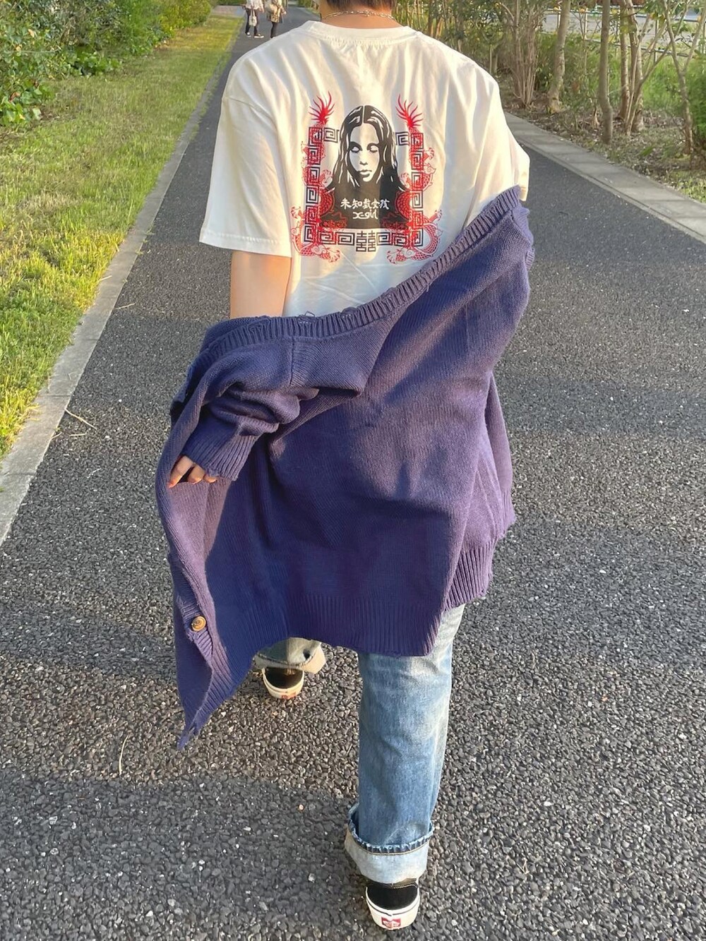 ブルー系のデニムパンツ、ブラック系のスニーカー、ホワイト系のTシャツ/カットソーを着用したレディースの春コーディネートの2枚目の写真