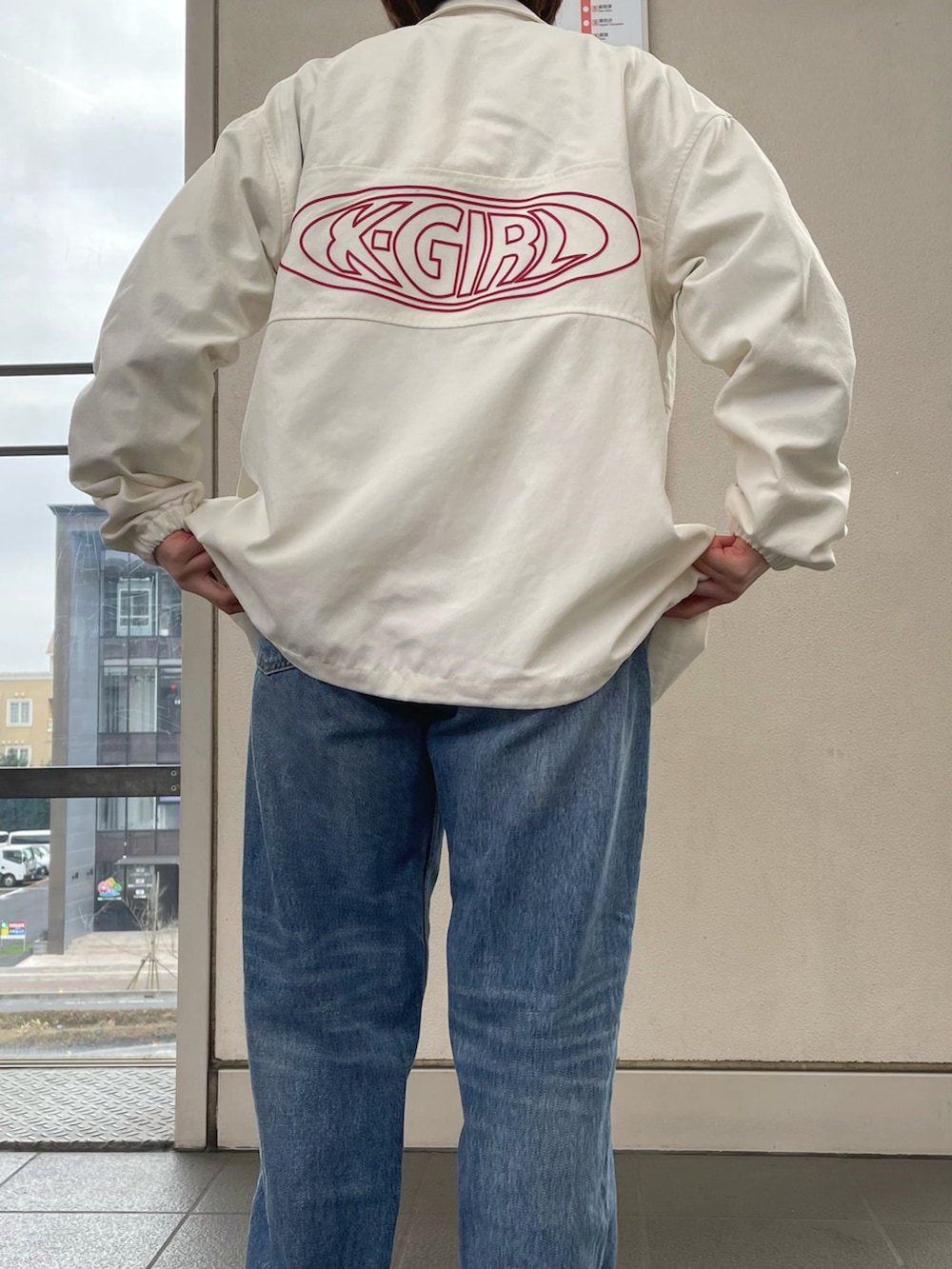 ブルー系のデニムパンツ、ホワイト系のナイロンジャケット、ブラック系のTシャツ/カットソーを着用したレディースの春コーディネートの2枚目の写真