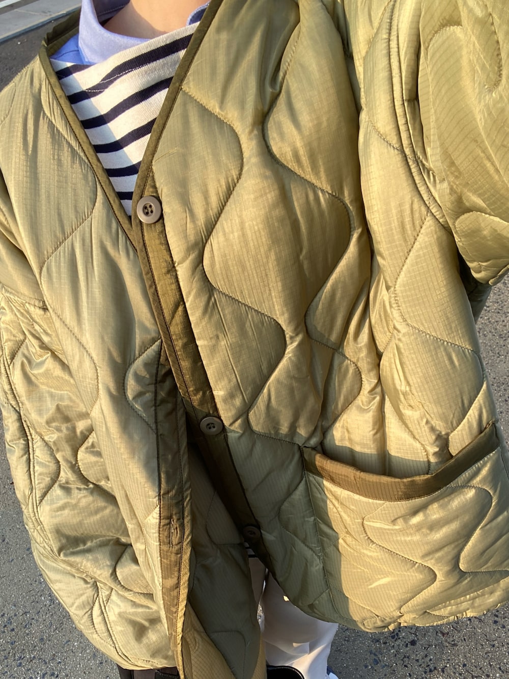 グリーン系のブルゾン、ブルー系のTシャツ/カットソー、ホワイト系のその他パンツを着用したレディースの冬コーディネートの2枚目の写真