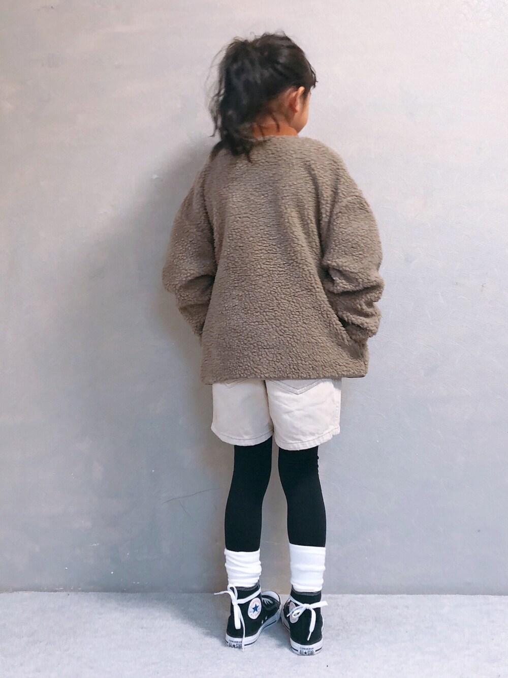 ホワイト系のデニムパンツ、イエロー系のニット/セーター、ベージュ系のノーカラージャケットを着用したキッズの冬コーディネートの2枚目の写真