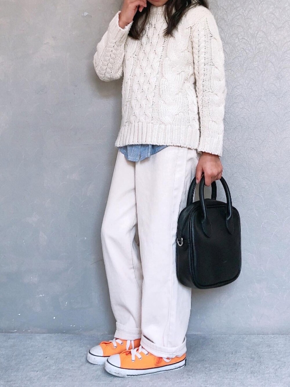 ブラック系のボストンバッグ、オレンジ系のスニーカー、ベージュ系のデニムパンツを着用したキッズの冬コーディネートの3枚目の写真