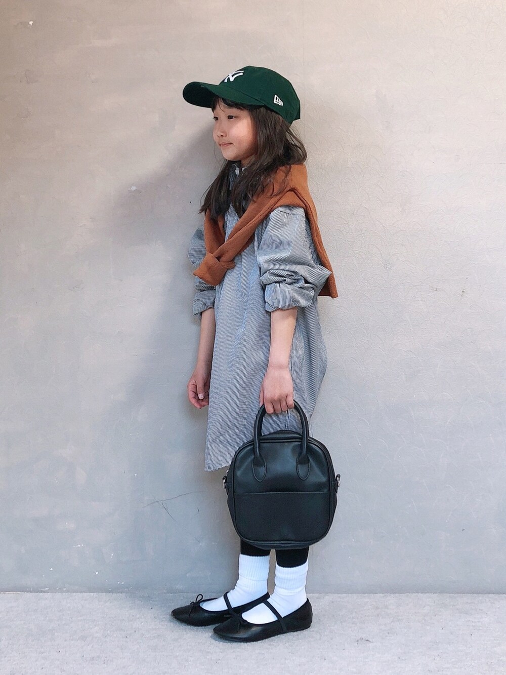 イエロー系のニット/セーター、ブラック系のボストンバッグ、ブラック系のバレエシューズを着用したキッズの春コーディネートの2枚目の写真