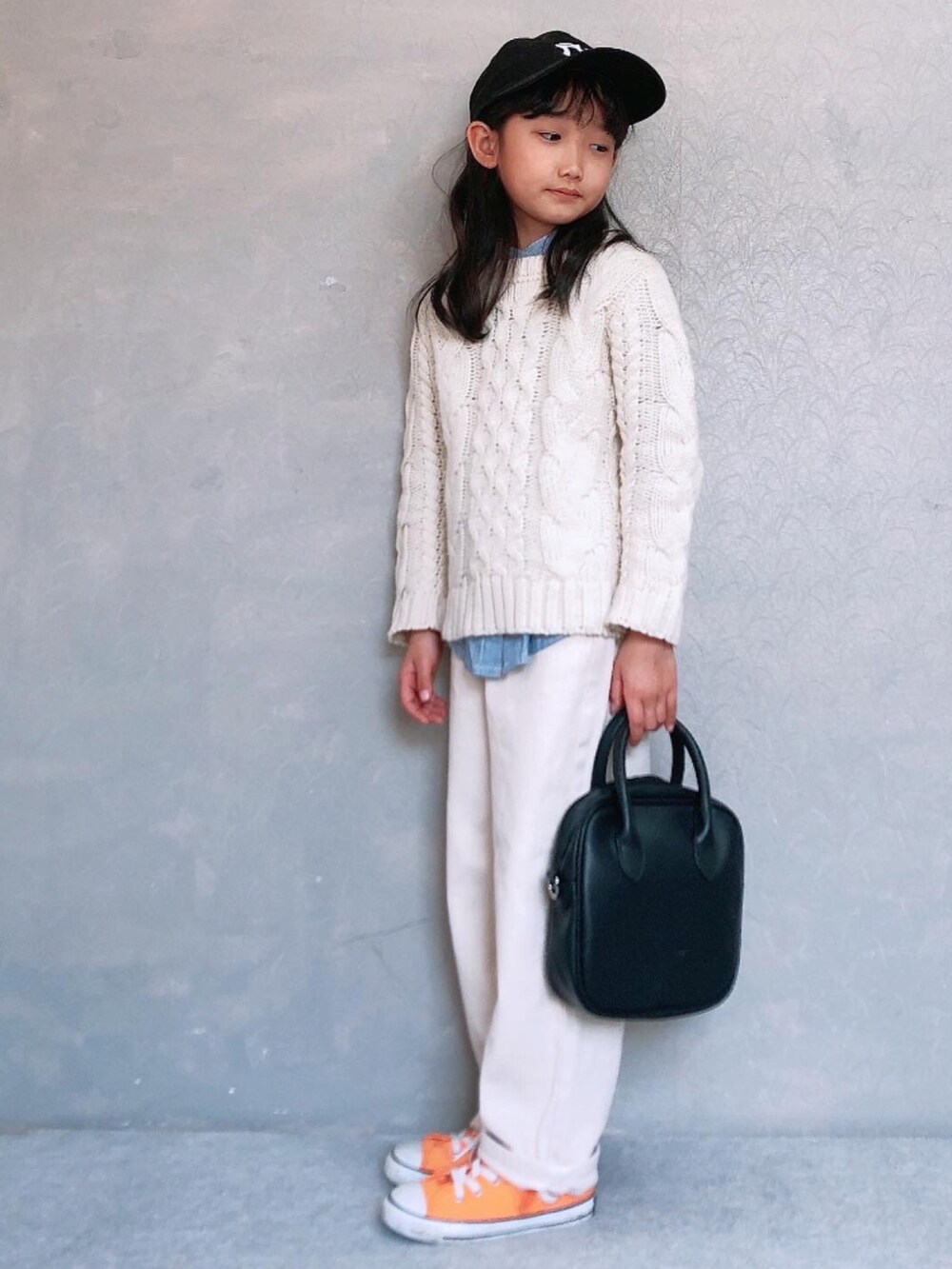 ブラック系のボストンバッグ、オレンジ系のスニーカー、ベージュ系のデニムパンツを着用したキッズの冬コーディネートの2枚目の写真