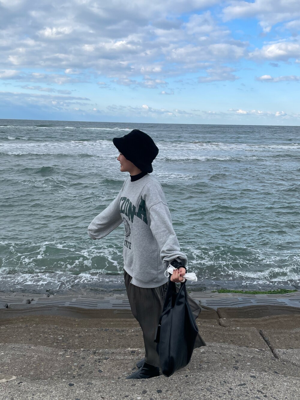 グレー系のスウェット、グレー系のスカート、ブラック系のハットを着用したレディースの秋コーディネートの3枚目の写真